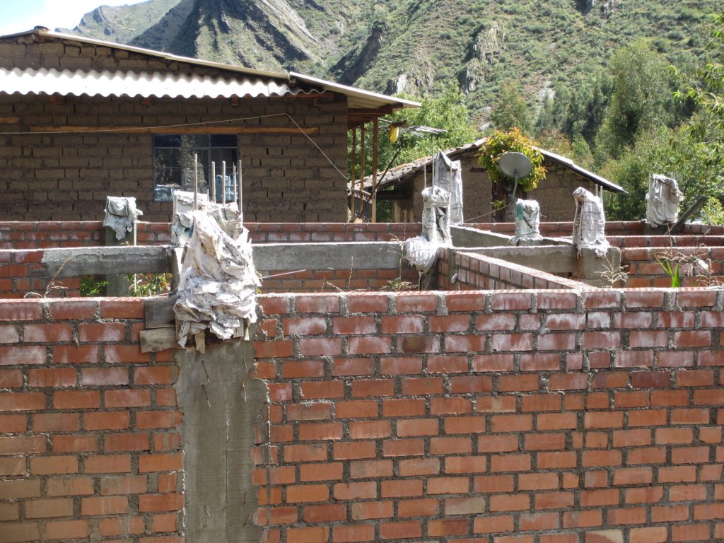 The mixed blessing of progress in Llamac: half-built homes and satellite dishes.